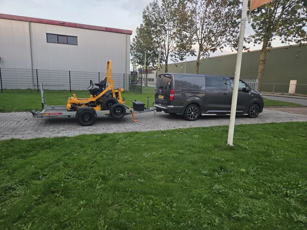 Bestelbus met aanhanger en een zero-turn maaier, klaar om op te halen of te brengen