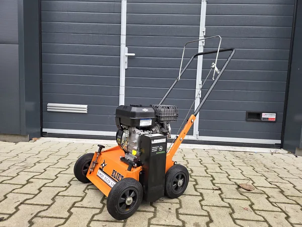 Oranje tuinmachine op benzine voor een garagedeur